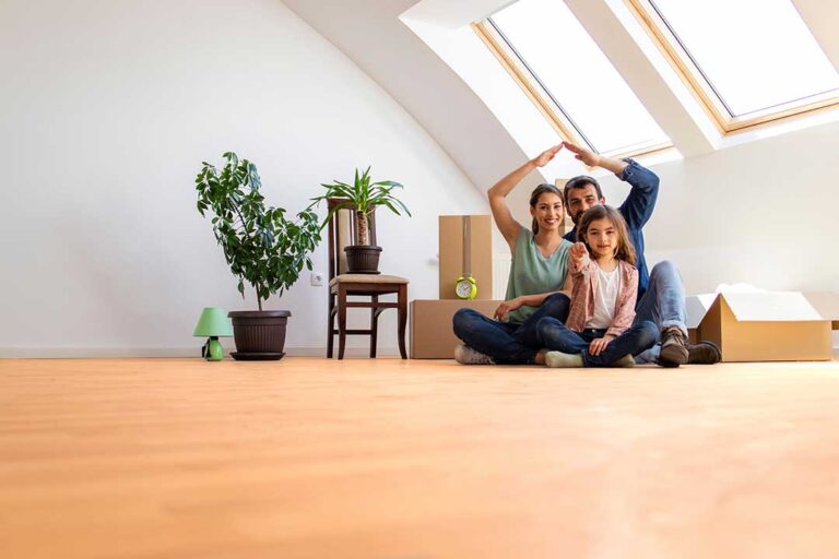 First-time buyers review home documents at a kitchen table beside a calculator and inspection checklist.